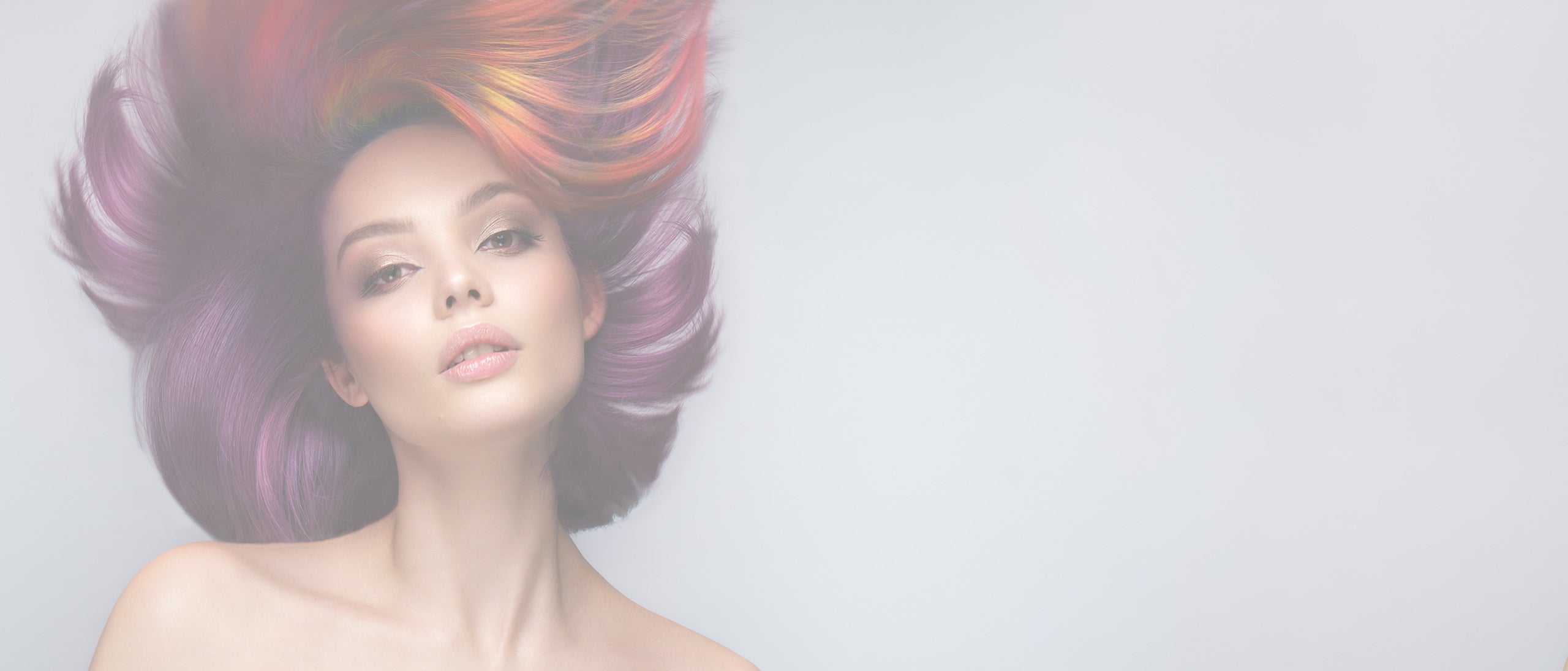 Kvinde med flydende, flerfarvet hår i bevægelse mod lys baggrund.