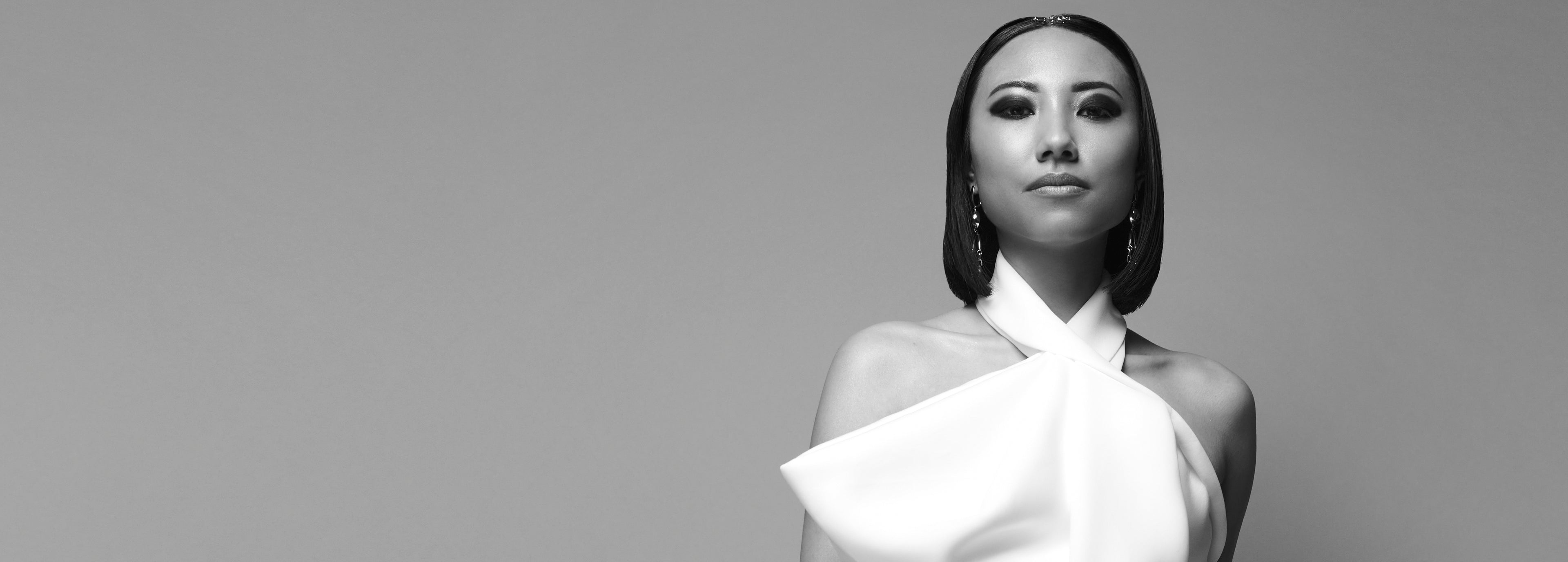 Sort/hvidt billede af kvinde med glat, kort pagehår og hvid halterneck-top.