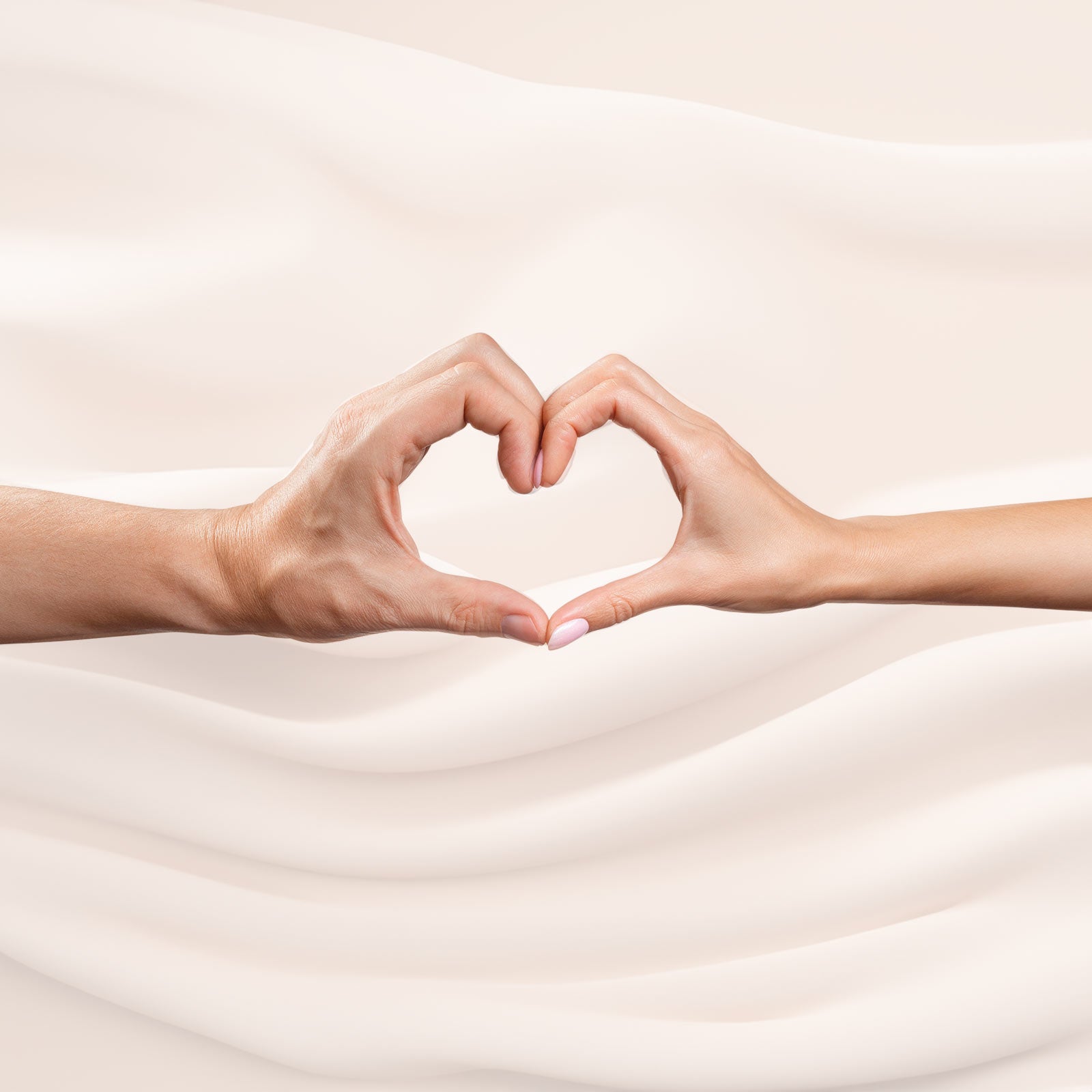 To hænder former et hjerte mod en lys, bølget baggrund.