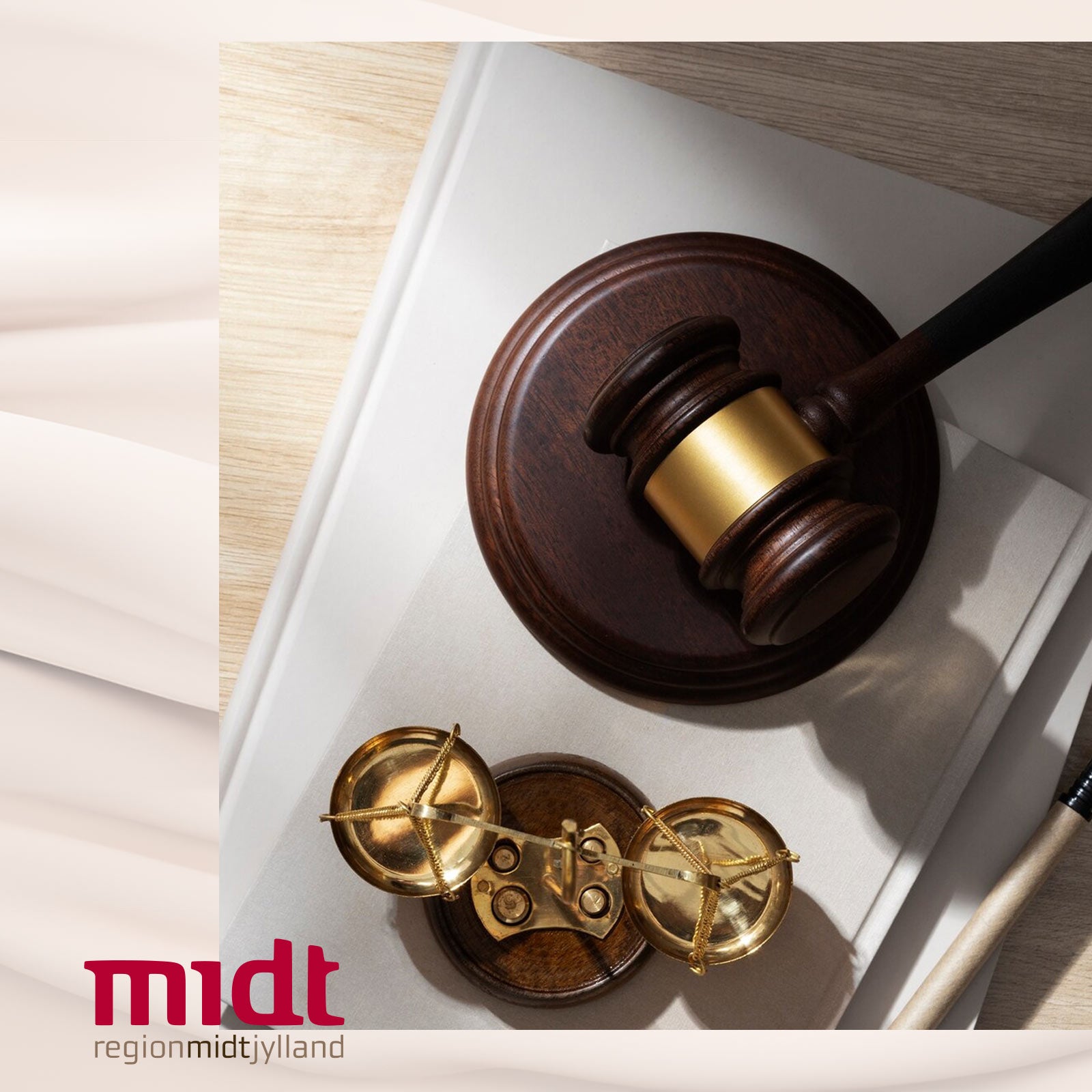 Dommerhammer og vægtskål på et skrivebord med Region Midtjylland-logo i hjørnet.