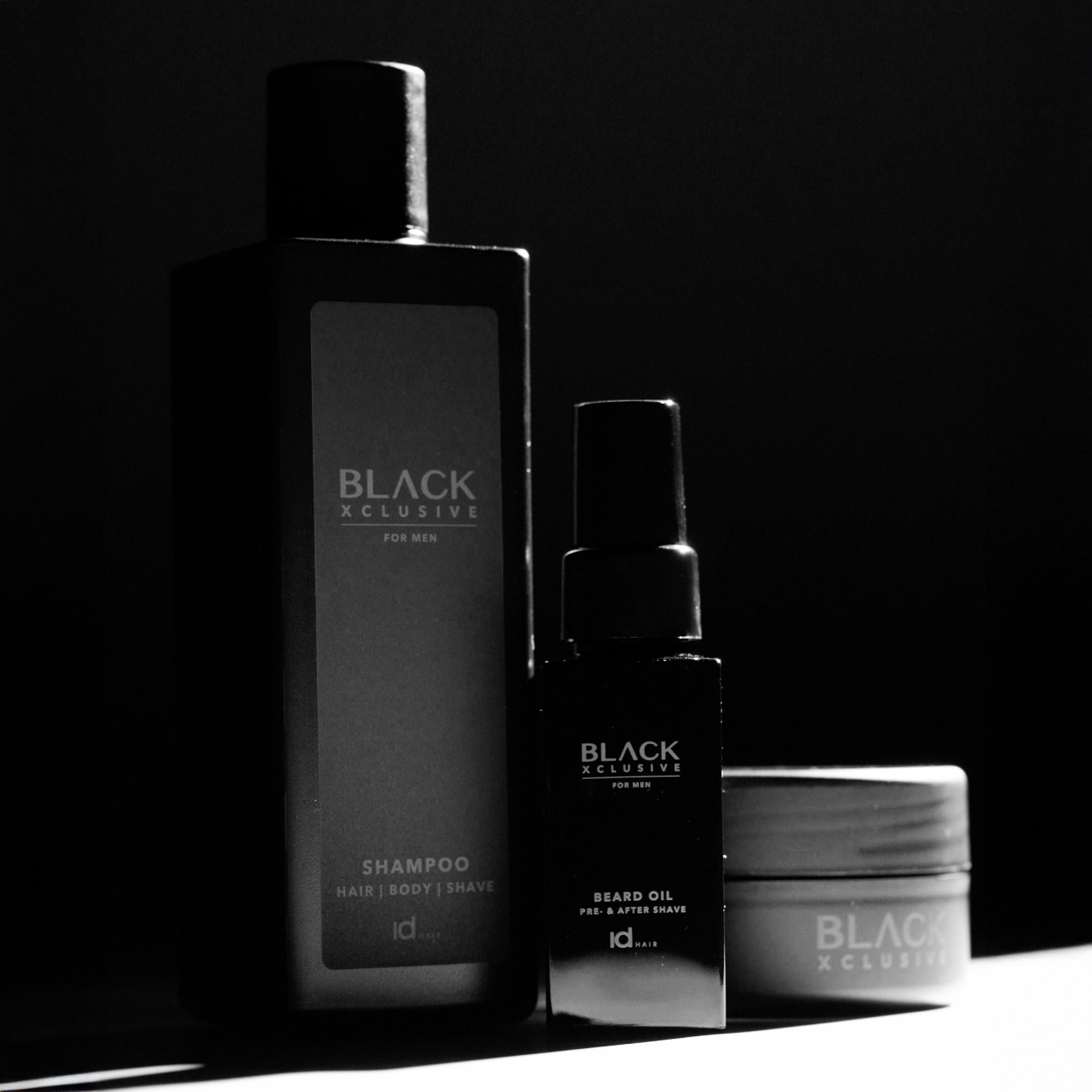 Black Xclusive Shampoo, Beard Oil og Wax fra IdHAIR. Stilren produktopstilling i et mørkt, maskulint design.