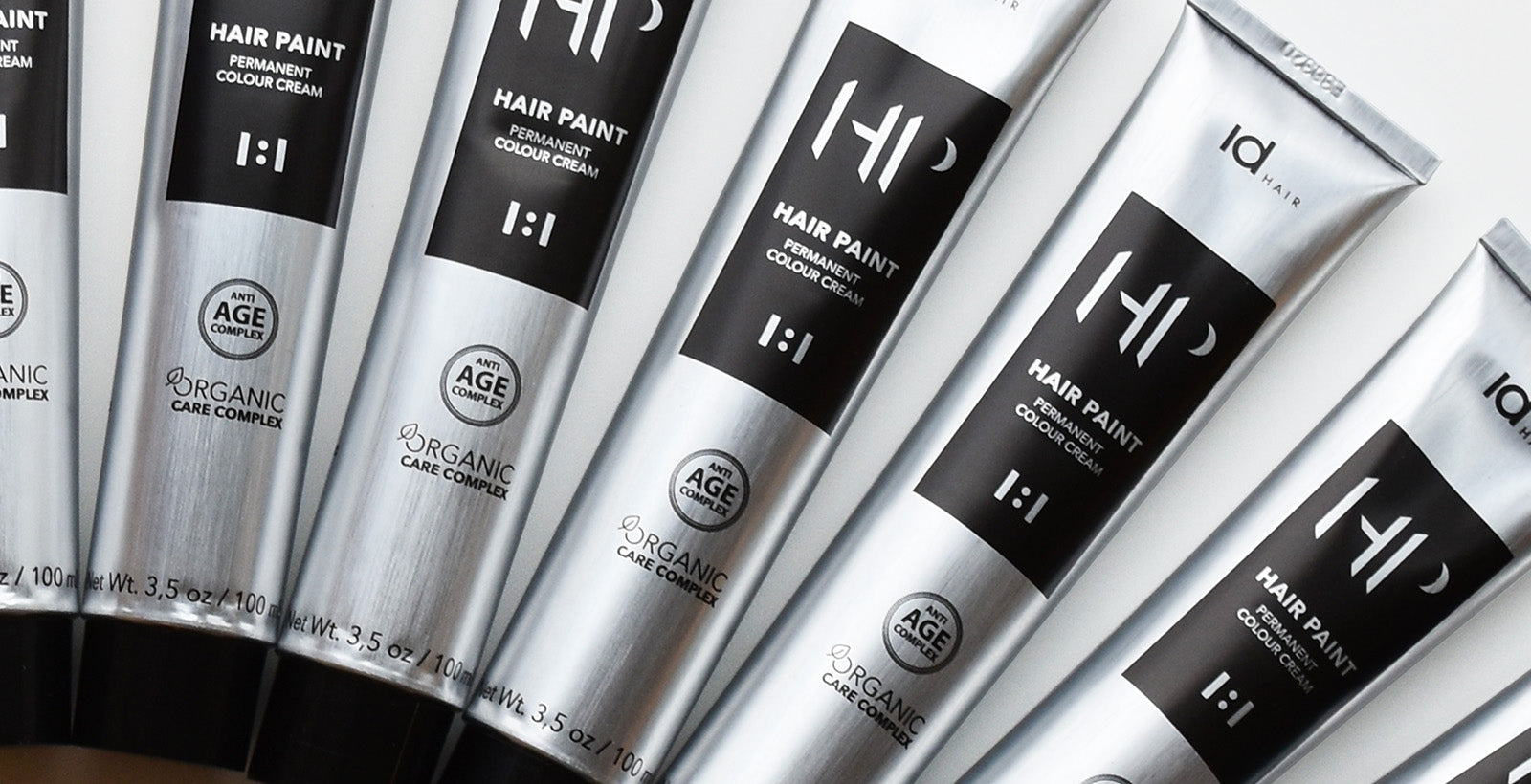 Sølvfarvede IdHAIR Hair Paint farvetuber med sort label og tekst.