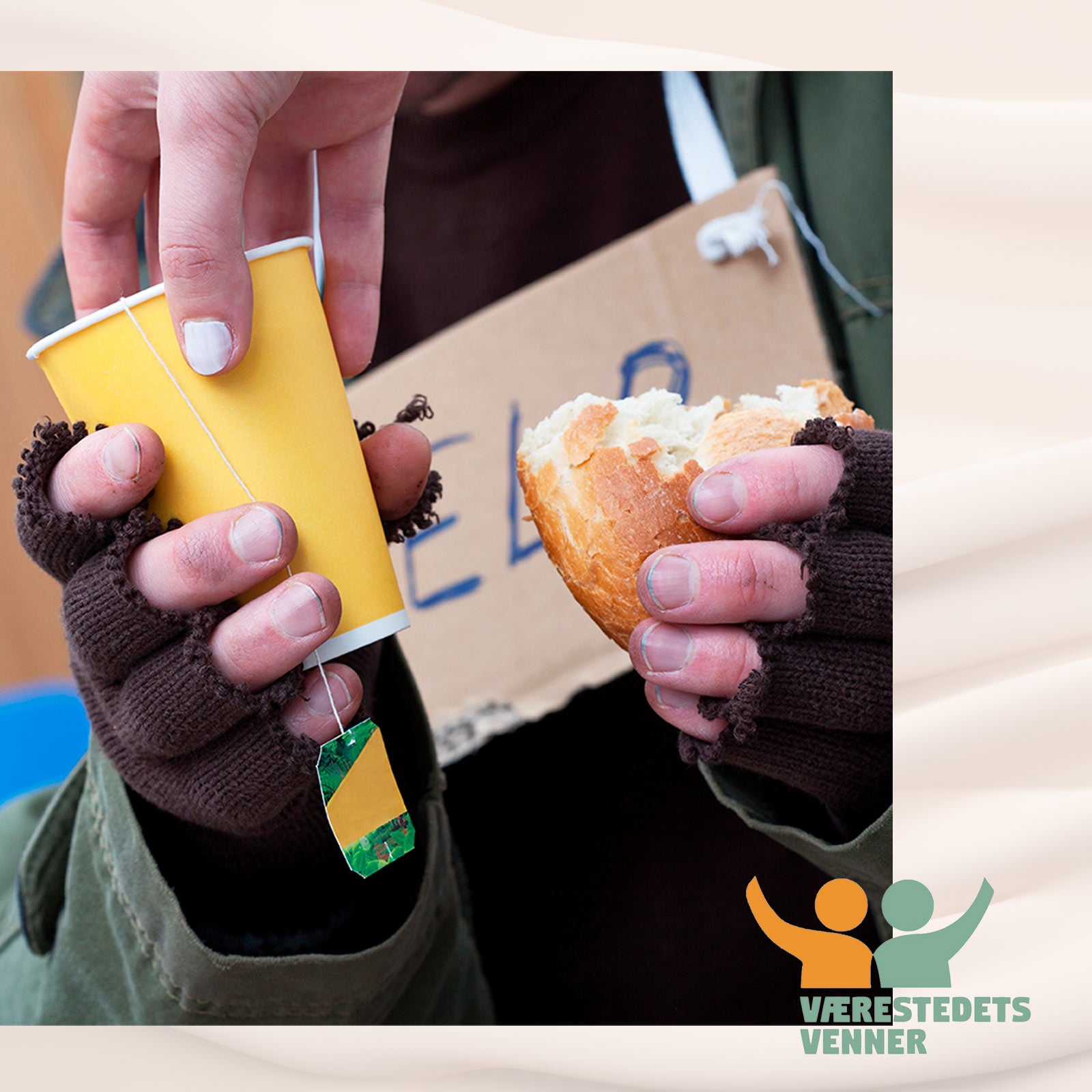 Person med fingerløse vanter holder et stykke brød og en gul papkop med te.